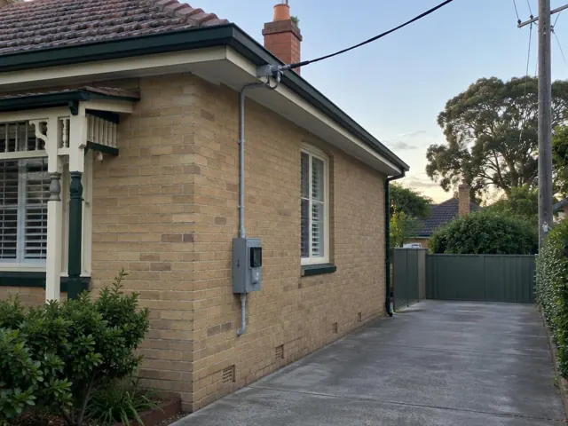 Brick house exterior with overhead service cable, point-of-attachment bracket and meter box in Wallsend